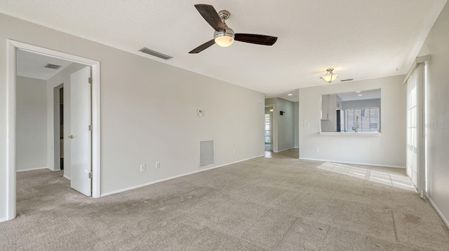 unfurnished living room with light carpet, ceiling fan, and a textured ceiling