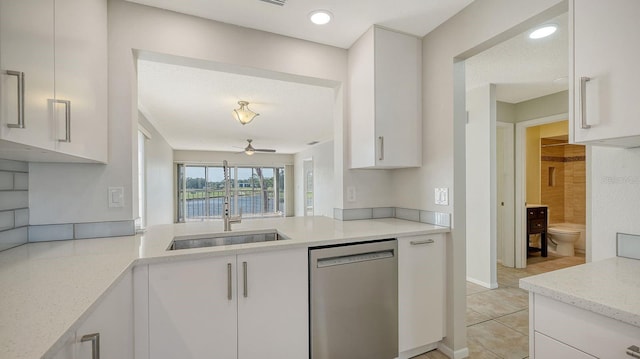 kitchen with light stone countertops, white cabinets, ceiling fan, sink, and dishwasher