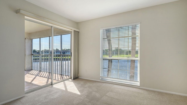 spare room featuring a water view and light colored carpet