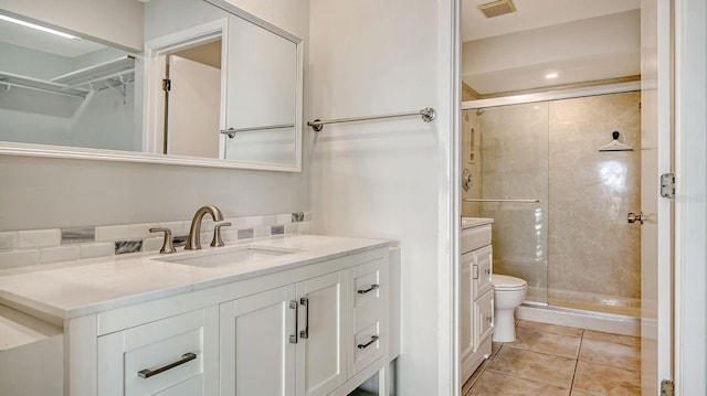 bathroom featuring toilet, vanity, tile patterned floors, and a shower with door