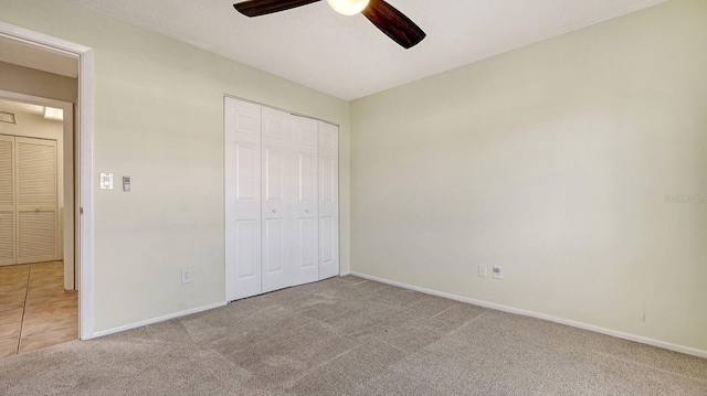 unfurnished bedroom with light carpet, a closet, and ceiling fan