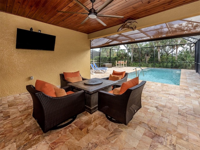 view of swimming pool featuring an outdoor living space, glass enclosure, ceiling fan, and a patio area