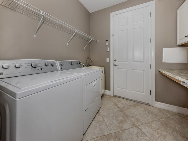 laundry area with separate washer and dryer, sink, light tile patterned floors, and cabinets