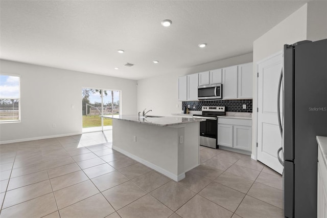 kitchen with white cabinetry, sink, a center island with sink, light tile patterned floors, and appliances with stainless steel finishes