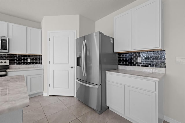 kitchen with tasteful backsplash, white cabinets, stainless steel appliances, and light tile patterned floors