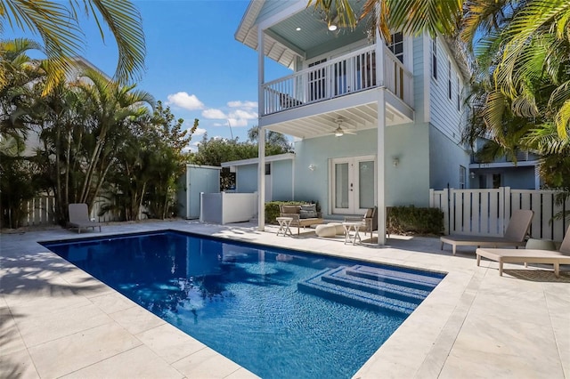 back of property with french doors, a balcony, ceiling fan, a patio, and a fenced in pool