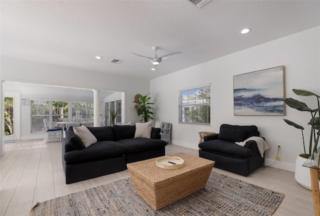 living room featuring ceiling fan, plenty of natural light, and a textured ceiling