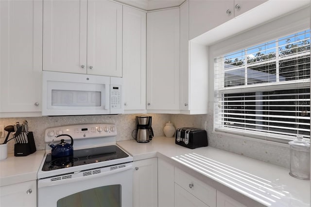 kitchen with white appliances, tasteful backsplash, and white cabinetry