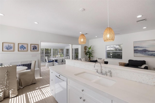 kitchen featuring white dishwasher, sink, light tile patterned floors, decorative light fixtures, and white cabinetry