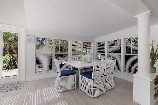 sunroom / solarium featuring decorative columns, a wealth of natural light, and vaulted ceiling