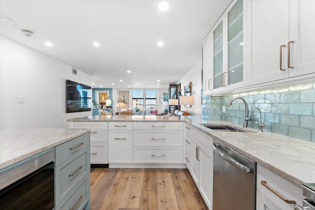 kitchen with dishwasher, white cabinets, light hardwood / wood-style flooring, and sink