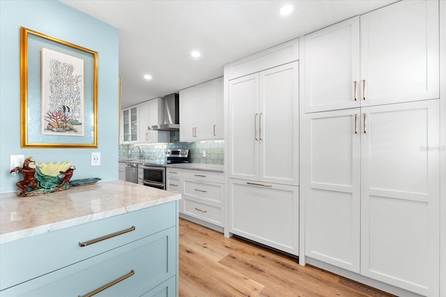 kitchen featuring white cabinetry, wall chimney range hood, stainless steel appliances, and tasteful backsplash