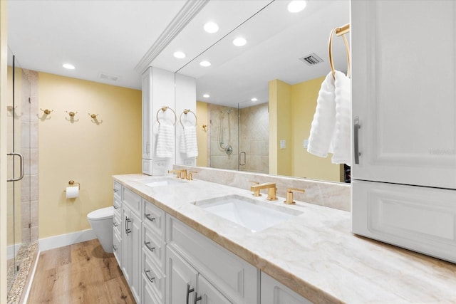 bathroom featuring vanity, toilet, wood-type flooring, and a shower with door