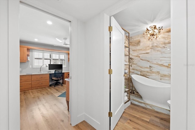 bathroom featuring ceiling fan, wood-type flooring, a tub, and tile walls