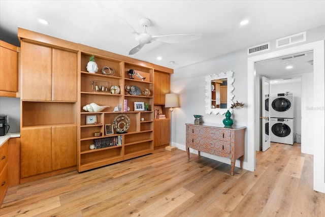 interior space featuring stacked washing maching and dryer, light hardwood / wood-style flooring, and ceiling fan