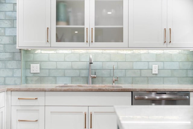 kitchen with backsplash, white cabinetry, dishwasher, and sink