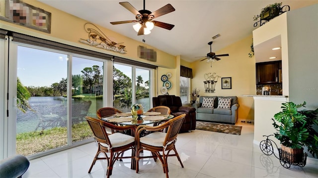 dining space featuring light tile patterned floors, a water view, vaulted ceiling, and ceiling fan