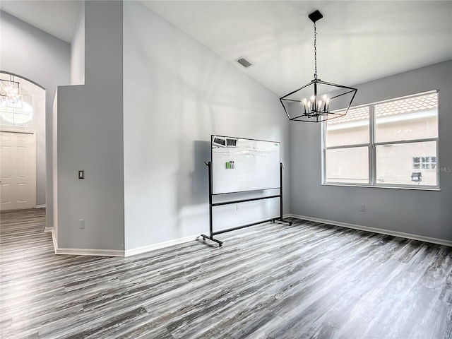 unfurnished dining area with hardwood / wood-style floors and an inviting chandelier