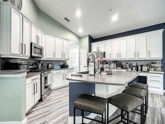 kitchen featuring a kitchen island with sink, white cabinets, and stainless steel appliances