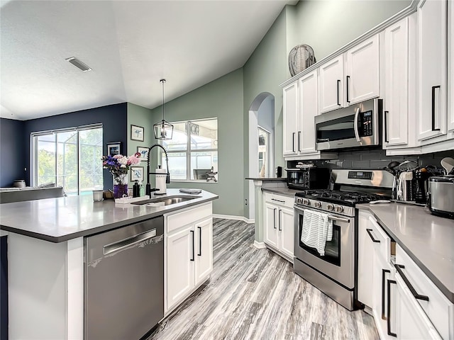 kitchen featuring white cabinets, stainless steel appliances, vaulted ceiling, and sink