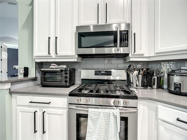 kitchen with white cabinets, stainless steel appliances, and tasteful backsplash