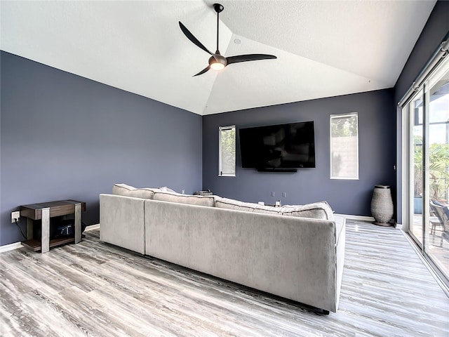 living room featuring ceiling fan, light hardwood / wood-style flooring, and vaulted ceiling