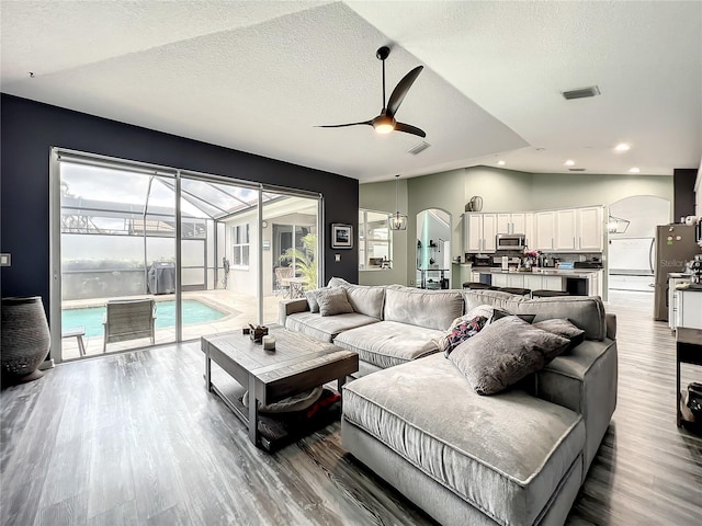 living room featuring a textured ceiling, hardwood / wood-style flooring, ceiling fan, and lofted ceiling