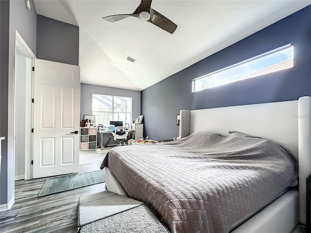 bedroom with a textured ceiling, ceiling fan, lofted ceiling, and hardwood / wood-style flooring