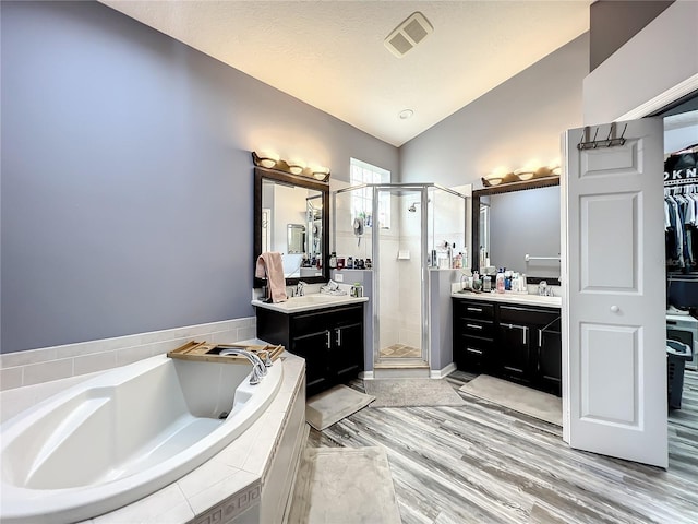 bathroom featuring hardwood / wood-style flooring, vanity, separate shower and tub, and vaulted ceiling