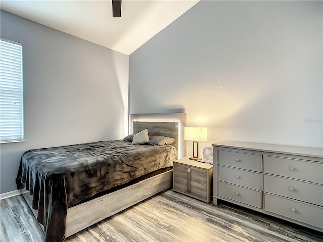 bedroom featuring ceiling fan, light wood-type flooring, and vaulted ceiling