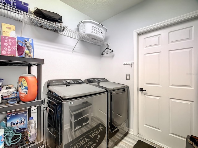 clothes washing area with hardwood / wood-style flooring and washing machine and clothes dryer