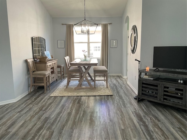 dining room featuring arched walkways, dark wood-type flooring, an inviting chandelier, and baseboards