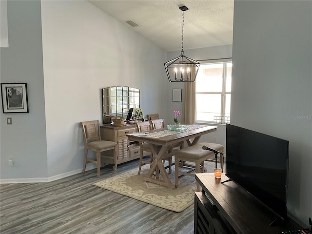 dining area featuring a textured ceiling, a chandelier, wood finished floors, visible vents, and baseboards