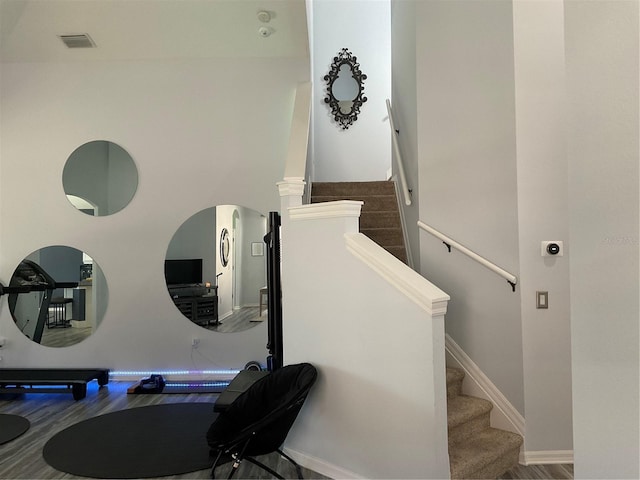 stairway with visible vents, baseboards, and wood finished floors