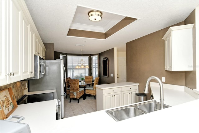 kitchen with kitchen peninsula, a tray ceiling, sink, white cabinetry, and light tile patterned flooring