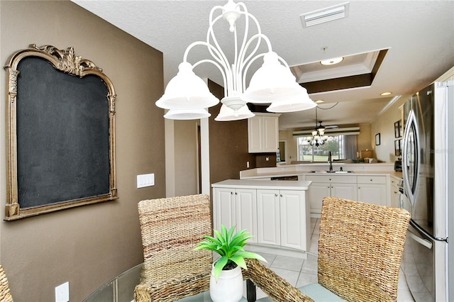 kitchen featuring stainless steel refrigerator, white cabinetry, sink, kitchen peninsula, and crown molding