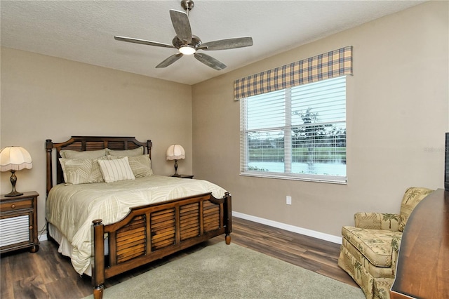 bedroom featuring ceiling fan, dark wood-type flooring, and a textured ceiling