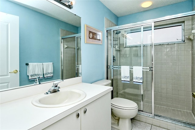 bathroom featuring tile patterned floors, a textured ceiling, toilet, a shower with door, and vanity