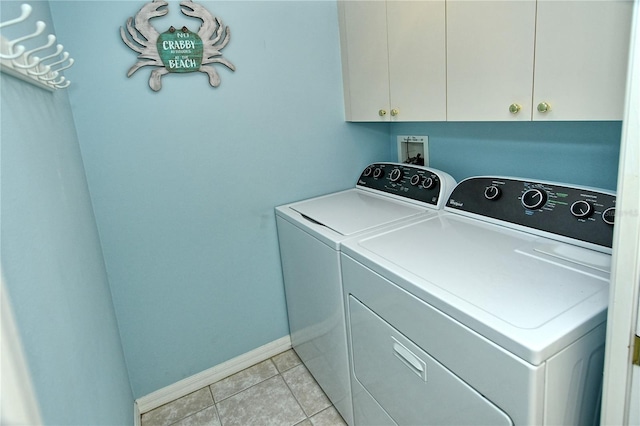 laundry area with cabinets, washing machine and dryer, and light tile patterned floors