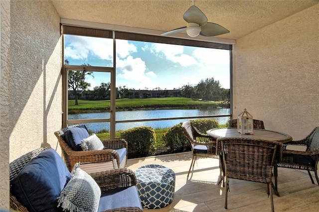 sunroom featuring ceiling fan and a water view