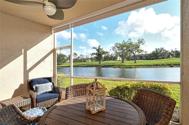 sunroom / solarium with ceiling fan and a water view