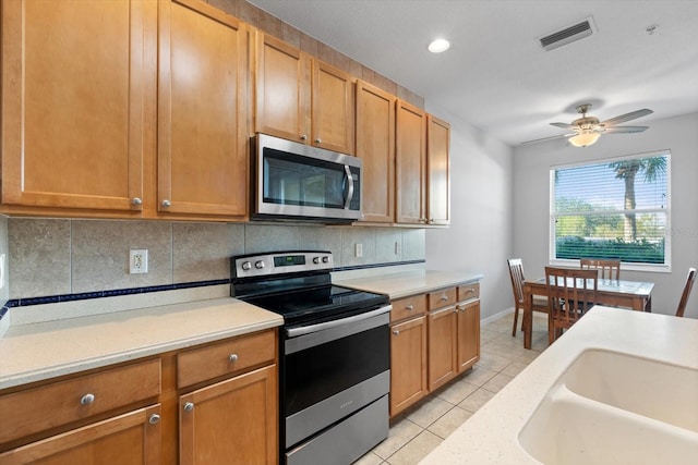 kitchen with backsplash, ceiling fan, light tile patterned flooring, and stainless steel appliances