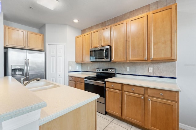 kitchen featuring appliances with stainless steel finishes, backsplash, a kitchen island with sink, sink, and light tile patterned floors