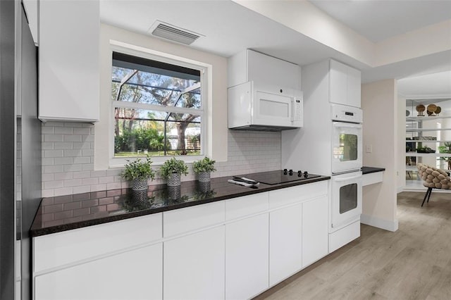 kitchen with white cabinets, decorative backsplash, white appliances, and light hardwood / wood-style flooring