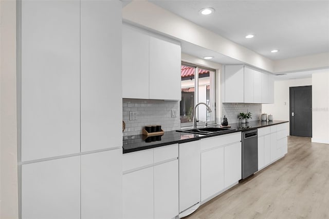 kitchen with backsplash, white cabinets, sink, and light hardwood / wood-style flooring