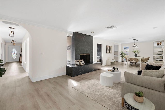 living room with light wood-type flooring, a premium fireplace, and ornamental molding