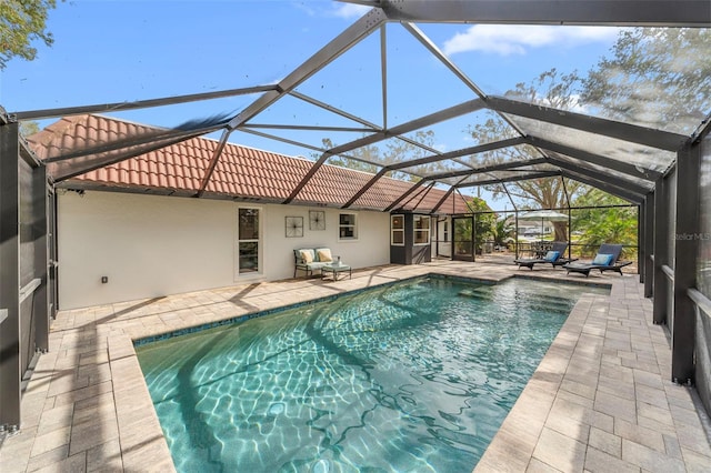 view of swimming pool featuring glass enclosure and a patio