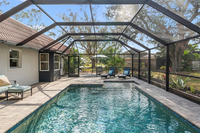 view of pool with glass enclosure and a patio area