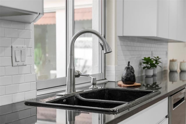 kitchen featuring backsplash, white cabinetry, sink, and stainless steel dishwasher