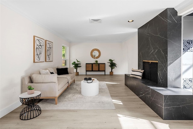 living room with light wood-type flooring, ornamental molding, and a premium fireplace